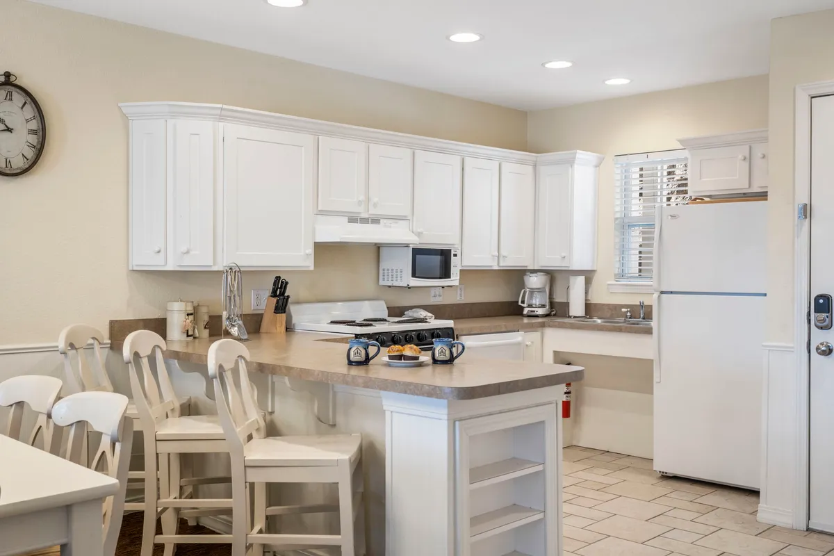 This image showcases a spacious, inviting main kitchen area with white cabinetry, a large kitchen island, and an adjacent dining space. The setup is open and bright, perfect for group gatherings and communal cooking.