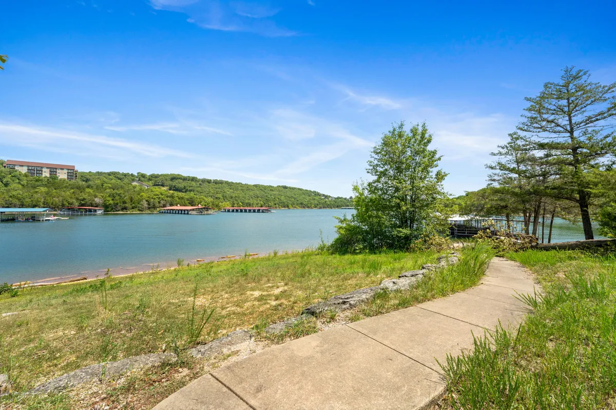 A serene view featuring a winding pathway alongside the lake, framed by trees and gentle hills, ideal for morning walks, birdwatching, and enjoying peaceful moments with pets.