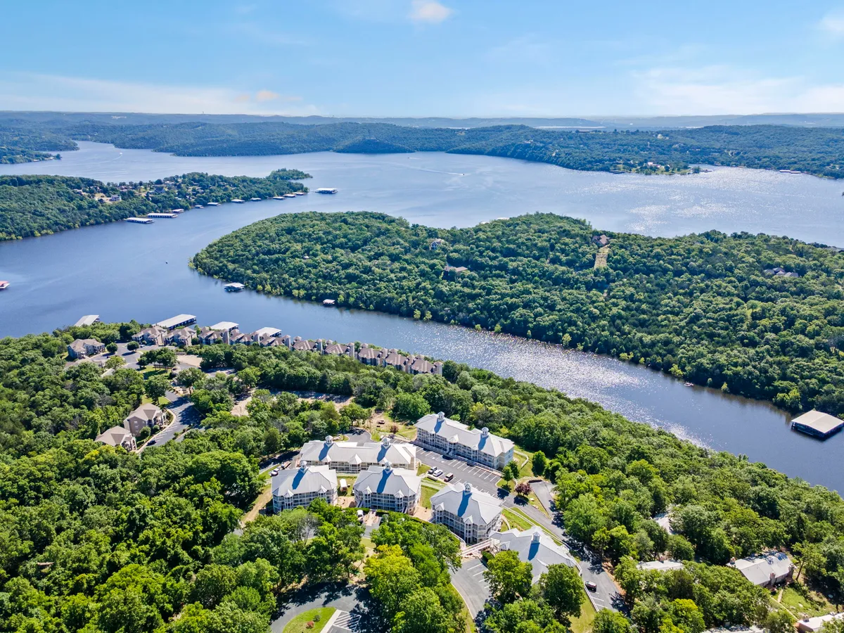 A tranquil sunset view over the river, framed by gently rolling hills and residential buildings in the background. The scene highlights boating and fishing on the water, as well as hiking trails and areas for relaxing by the shore. Wildlife and community spaces are subtly visible, emphasizing connection to nature and local gatherings.